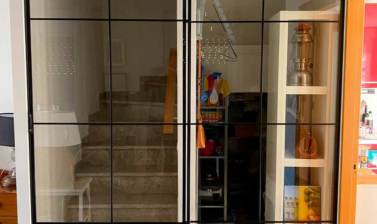 Puerta corredera de escalera y hueco de escalera en hierro color negro y cristal