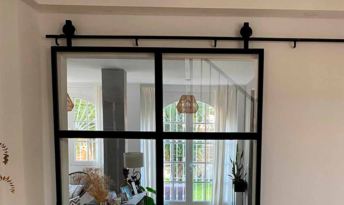 Puerta corredera en hierro y cristal con carril visible